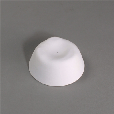 A small circular white ceramic mold for fusing glass on a grey background. It has been shaped into a dome, though the top has been flattened and carved inwards slightly.