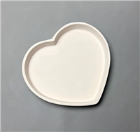 A heart shaped white ceramic mold for fusing glass on a grey background. The outer rim of the heart is raised in a continuous straight wall, creating a large, flat, heart shaped cavity within.