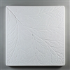 A square tile made of white ceramic for texturing hot glass. The tile has the texture of a large leaf, with a primary vein beginning in the top left corner and extending diagonally down to the bottom right, with multiple smaller veins branching off.