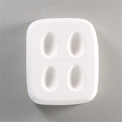 A rectangular white ceramic mold for fusing hot glass on a grey background. Four identical small egg shapes have been carved into it with equal space between them. The mold says LF16 in the very center.