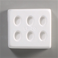 A rectangular white ceramic mold for fusing hot glass on a grey background. Six identical small ovals have been carved into it with equal spacing between them. LF20 is printed in the middle of the mold.
