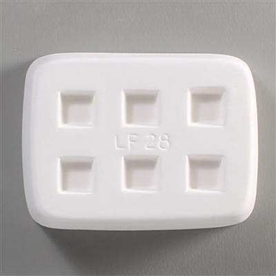 A rectangular white ceramic mold for fusing hot glass on a grey background. Six separate but identical squares have been carved into it with equal space between them. LF28 is carved onto the mold between them.