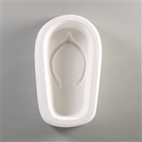 An oval, white ceramic mold for fusing hot glass on a grey background. A single flip-flop shoe has been carved into it.