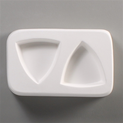 A rectangular white ceramic mold for fusing hot glass on a grey background. Two separate large triangles with rounded sides have been carved into it with equal space between them.