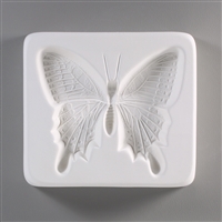 A square, white ceramic mold for fusing hot glass on a grey background. A very detailed flat swallowtail butterfly has been carved into it.