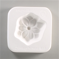 A square, white ceramic mold for fusing hot glass on a grey background. A simple flat magnolia flower with a deep center has been carved into it. The mold has Little Fritters #11 Magnolia engraved on the sides in script.