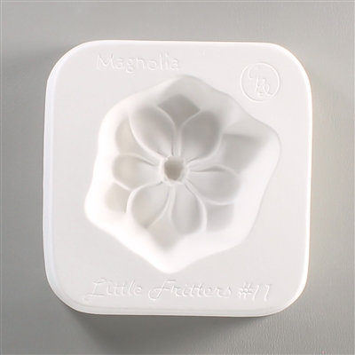 A square, white ceramic mold for fusing hot glass on a grey background. A simple flat magnolia flower with a deep center has been carved into it. The mold has Little Fritters #11 Magnolia engraved on the sides in script.