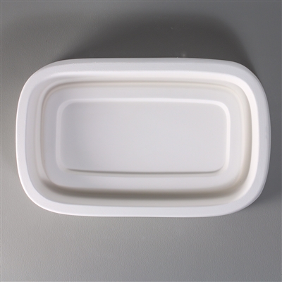 A rounded rectangular, white ceramic mold for fusing hot glass on a grey background. A large, deep rectangle has been carved into it with a shallower smaller rectangle inside that, forming a dish shape.