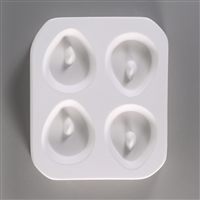 A rectangular, white ceramic mold for fusing hot glass on a grey background. Four small, rounded tear shapes have been carved into it with equal distance between them. Each tear has a post towards its top to allow for stringing into jewelry after firing.