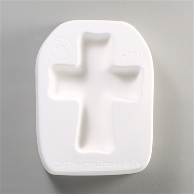 A roughly rectangular, white ceramic mold for fusing hot glass on a grey background. A simple small cross has been carved into it.