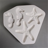 A roughly triangular white ceramic mold for fusing hot glass on a grey background. Two seahorses and two starfish have been carved into it. Each animal has a slightly different design than its counterpart, but all are similarly sized.