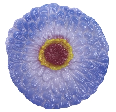 A flat fused glass zinnia flower on a transparent background. The petals are dark lilac on the outside fading into lavender towards the center, with a small bit of magenta around the center itself. The center has a ring of yellow around a dark red middle