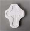 A cross-shaped white ceramic mold for fusing hot glass on a grey background. An ornate and intricately designed cross has been carved into it.