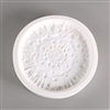 A circular white ceramic mold for fusing hot glass on a grey background. A detailed but flattened mushroom cap has been carved into it. The cap takes up most of the mold, but there is a small border of empty space around it.