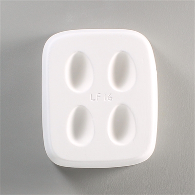 A rectangular white ceramic mold for fusing hot glass on a grey background. Four identical small egg shapes have been carved into it with equal space between them. The mold says LF16 in the very center.