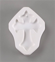 A cross-shaped white ceramic mold for fusing hot glass on a grey background. A simple cross has been carved into it. The top of the cross has a post in it, allowing for the finished piece to be strung into jewelry.