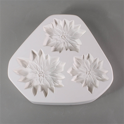 A triangular white ceramic mold for fusing hot glass on a grey background. Three flat detailed poinsettia flowers have been carved into it. Each flower is a slightly different size, with the bottom left being the largest and the bottom right the smallest.