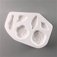 A roughly oval-shaped white ceramic mold for fusing hot glass on a grey background. Two flat rose flowers, one closed rose bud, and three slender leaves have been carved into it. The rose flowers are the same size, but each leaf is differently sized.