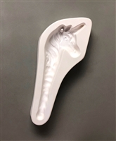 A long white ceramic mold for fusing hot glass on a grey background. A profile of a unicorn face with a neck tapering into an icicle has been carved into it. There is a post tucked in the unicornâ€™s ear allowing for hanging after firing.
