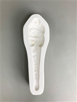 A long white ceramic mold for fusing hot glass on a grey background. A cat in a knit cap, scarf, and mittens and a body tapering into an icicle has been carved into it. The hat has a post in it allowing for hanging after firing.