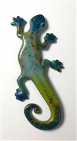 A fused glass lizard on a white background. The lizardâ€™s body is primarily shades of blue and green, but its body has been speckled with small points of black, orange, and green, especially along its tail and head. Its eyes are green with black pupils.