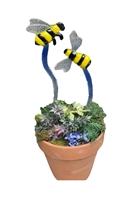 Two fused glass stakes with bees on top displayed in a pot with greenery. The stakes fade down blue to white, and the bees are bright yellow and black with grey wings. The taller left bee is in profile with visible legs. The right is a top-down view.
