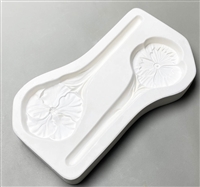 A roughly rectangular white ceramic mold for fusing hot glass on a grey background. Two garden stakes, one topped with a pansy flower and the other topped with a hibiscus flower, have been carved into it. The stakes face opposite directions.