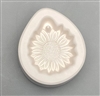 A teardrop-shaped white ceramic mold for fusing hot glass on a grey background. A small, detailed sunflower has been carved into it. There is a post above the top petals allowing for stringing into jewelry after firing.