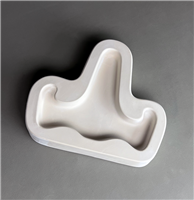 A T-shaped white ceramic mold for fusing hot glass on a grey background. A simple flat easel shape with a long back part and two slightly curved arms on either side has been carved into it.