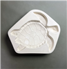 A white ceramic mold for fusing hot glass on a grey background. A large and detailed top-down view of a sea turtle facing right has been carved into it.