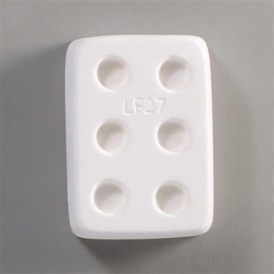 A rectangular white ceramic mold for fusing hot glass on a grey background. Six separate but identical circles have been carved into it with equal space between them. LF27 is carved onto the mold between them.