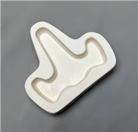 A T-shaped white ceramic mold for fusing glass on a grey background. A simple small flat easel shape with a long back part and two slightly curved arms on either side has been carved into it.