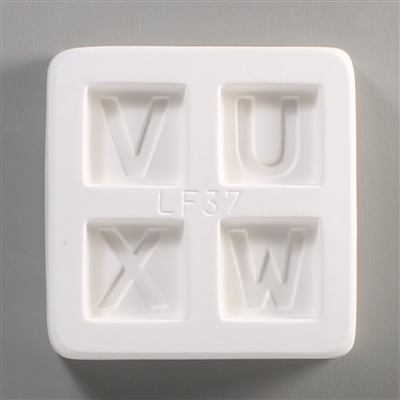 A square white ceramic mold for fusing hot glass on a grey background. Four separate but identically sized squares have been carved into it with equal space between them. Each square has one of the letters U, V, W, or X carved in block print in it.