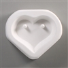 A triangular white ceramic mold for fusing hot glass on a grey background. A heart shape has been carved into it. There is a post on either side of the top of the heart allowing for the resulting glass piece to be strung or otherwise hung.