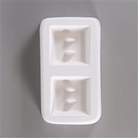 A rectangular white ceramic mold for fusing hot glass on a grey background. Two identical large square buttons, each with two posts to create holes for threading, have been carved into it with equal space between them.