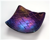 A small square fused glass dish. The glass is dark, opaque, and iridescent. It has been textured with a repeating pattern of small diamonds, and reflects the light in shades of purple, blue, and yellow.