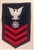 USCG Petty Officer First Class Rating Badge with Specialty:  QUARTERMASTER (QM) - E6 - Red on Blue Serge