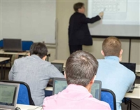 Classroom of people with laptops learning from an instructor