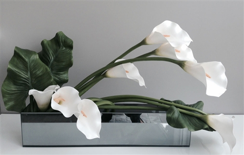 This beautiful floral arrangement features a clear glass base with white Callas Lilies on a vine carefully crafted to look seemingly real.