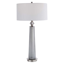Grayton Modern Lamp. This sleek table lamp features a frosted art glass base in light gray with white speckled texture. The piece is accented by polished nickel details and a crystal ornament. The hardback drum shade is covered in a white linen fabric.