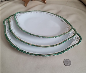 Preowned set of three antique Victoria Austria porcelain oval serving platters with decorative gold and green scalloped edges for elegant dining table centerpieces