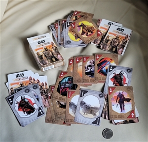 Open deck of Star Wars The Mandalorian playing cards spread out next to their original box and a coin marker for scale reference