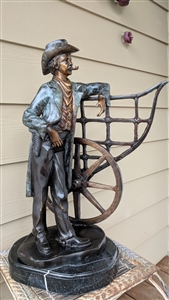 Massive vintage Trinx Ethelann bronze sculpture of a cowboy leaning on a wagon wheel mounted on a heavy green marble base
