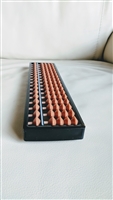 Vintage 17-digit plastic Soroban abacus with light brown beads and a black frame for display