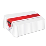 The Santa Suit Fabric Table Runner is red with white trim and at each end is a black belt with a silver glittery buckle and a white pom pom. It measures 13 inches wide and 5 feet 9 inches long. Made of fabric. Contains one per package. Surface wash only.